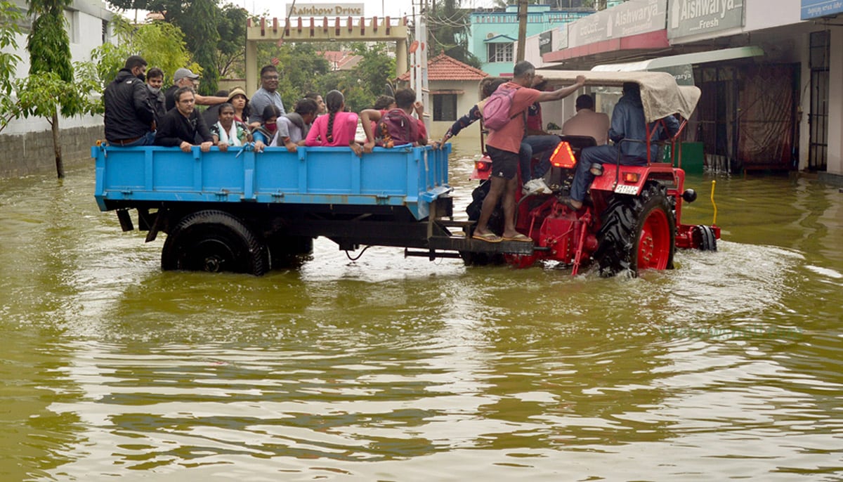 People travel in a tractor on a waterlogged road in Bengaluru