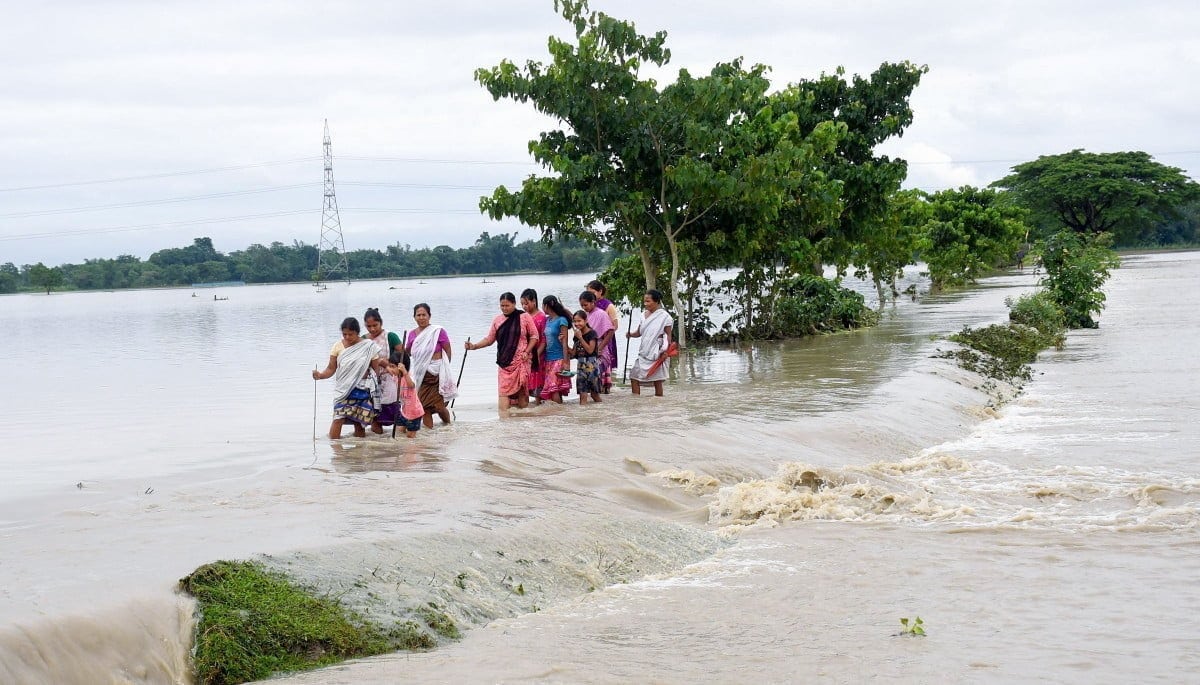 Villagers wade through the flood water at Dhamdama in Nalbari district of Assam on June 21