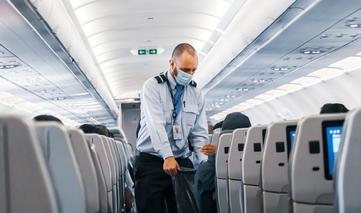 man in blue dress shirt standing in airplane airline employee